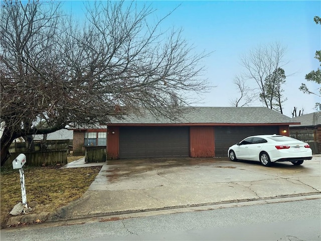 view of front of house with an outbuilding, an attached garage, a shingled roof, fence, and concrete driveway