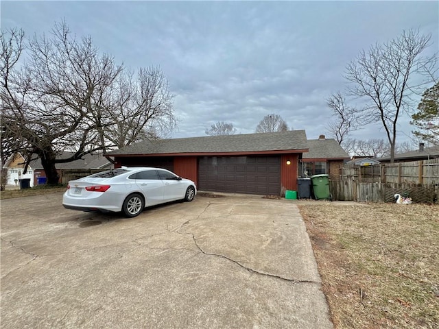 view of front facade featuring a garage, roof with shingles, driveway, and fence