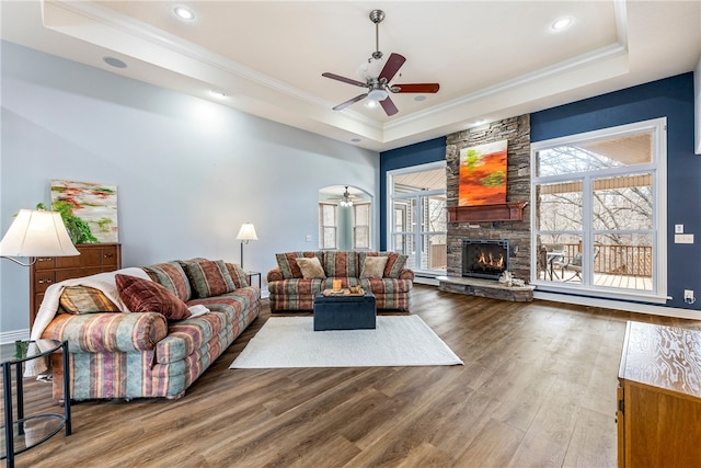 living room featuring crown molding, a fireplace, a raised ceiling, and hardwood / wood-style flooring