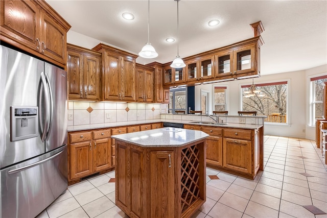 kitchen with stainless steel refrigerator with ice dispenser, sink, decorative light fixtures, kitchen peninsula, and a kitchen island