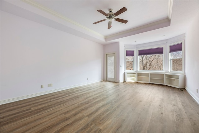 empty room with crown molding, hardwood / wood-style floors, a tray ceiling, and ceiling fan