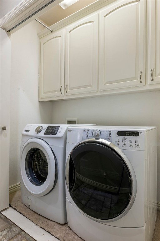 clothes washing area with cabinets and washer and dryer