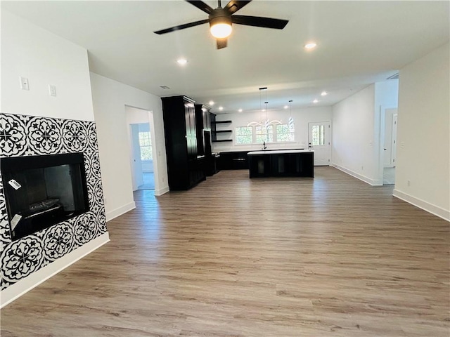 living room with dark wood-type flooring, ceiling fan, a fireplace, and sink