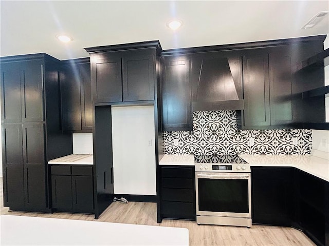 kitchen featuring backsplash, stainless steel electric range, light hardwood / wood-style floors, and premium range hood