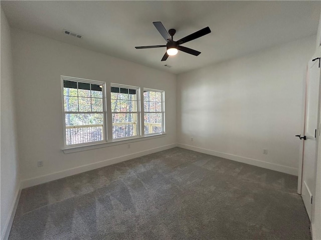 empty room with ceiling fan and dark colored carpet