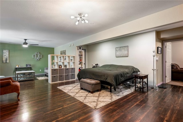 bedroom featuring dark hardwood / wood-style flooring, ceiling fan with notable chandelier, and a textured ceiling