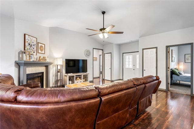 living room with a tiled fireplace, lofted ceiling, dark hardwood / wood-style floors, and ceiling fan