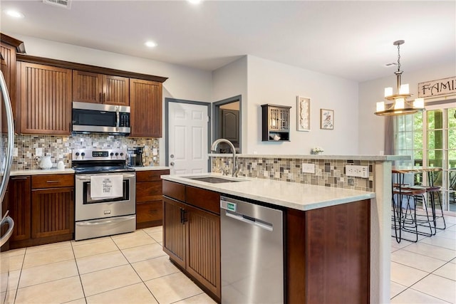 kitchen featuring hanging light fixtures, light tile patterned floors, sink, and appliances with stainless steel finishes