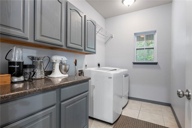 laundry area with cabinets, washing machine and dryer, and light tile patterned floors