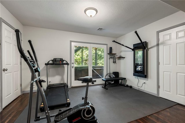 workout area with dark wood-type flooring and a textured ceiling