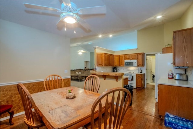 dining room with vaulted ceiling, hardwood / wood-style floors, and ceiling fan