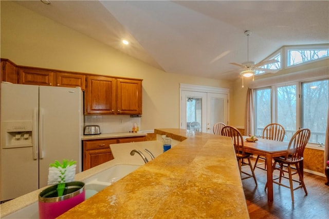 kitchen featuring lofted ceiling, sink, white fridge with ice dispenser, ceiling fan, and dark wood-type flooring