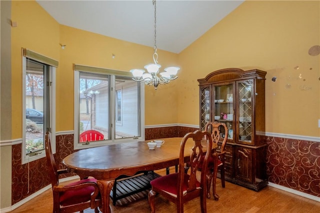 dining area featuring wood-type flooring, high vaulted ceiling, and an inviting chandelier