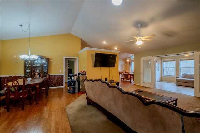 living room with vaulted ceiling, wood-type flooring, and ceiling fan with notable chandelier