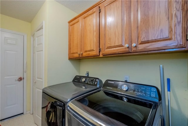 laundry area with cabinets, washing machine and dryer, and a textured ceiling