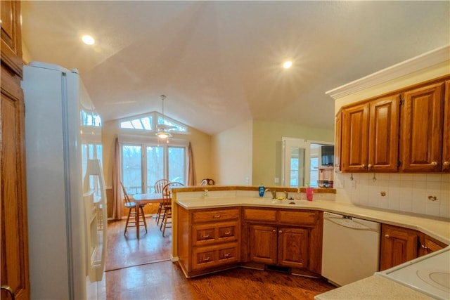 kitchen with dark hardwood / wood-style floors, lofted ceiling, hanging light fixtures, kitchen peninsula, and white appliances