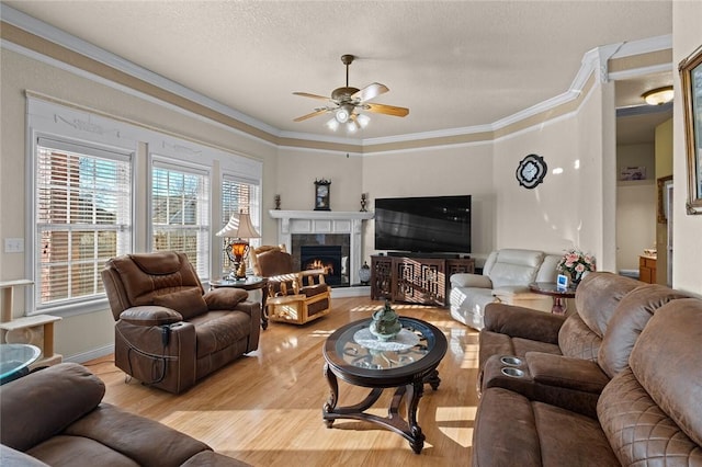 living room featuring crown molding, ceiling fan, a textured ceiling, and light wood-type flooring