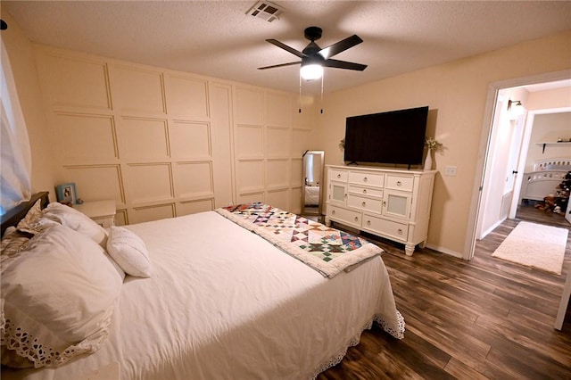 bedroom with ceiling fan, dark hardwood / wood-style flooring, and a textured ceiling