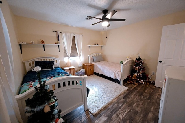 bedroom featuring dark hardwood / wood-style flooring, ceiling fan, and a textured ceiling