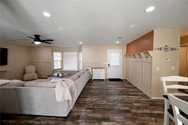 living room featuring ceiling fan, dark hardwood / wood-style floors, and a textured ceiling