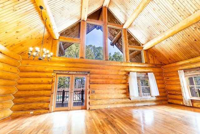 unfurnished living room featuring beam ceiling, french doors, a notable chandelier, wood finished floors, and wooden ceiling