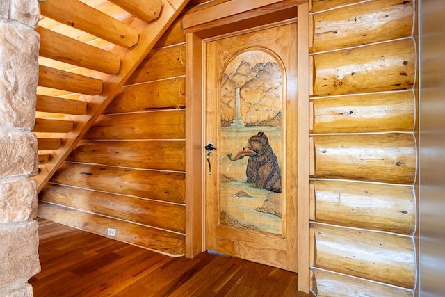 staircase with rustic walls and wood finished floors