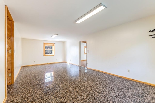 empty room featuring granite finish floor and baseboards