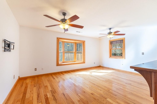 spare room with visible vents, ceiling fan, light wood-style flooring, and baseboards