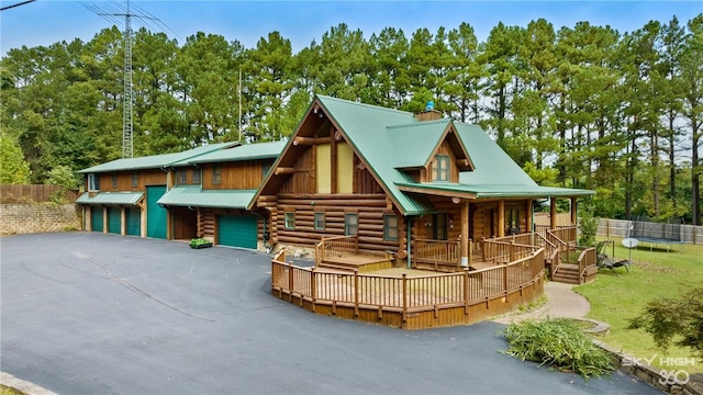 log home with a garage, log exterior, aphalt driveway, metal roof, and a trampoline