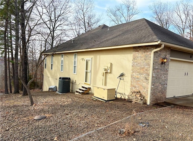 view of home's exterior with cooling unit and a garage