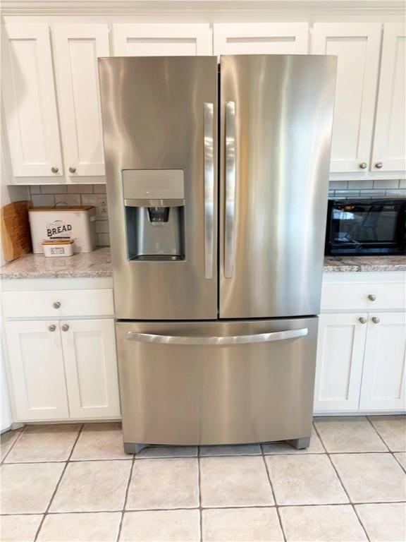 kitchen with white cabinetry, stainless steel fridge, and light tile patterned flooring