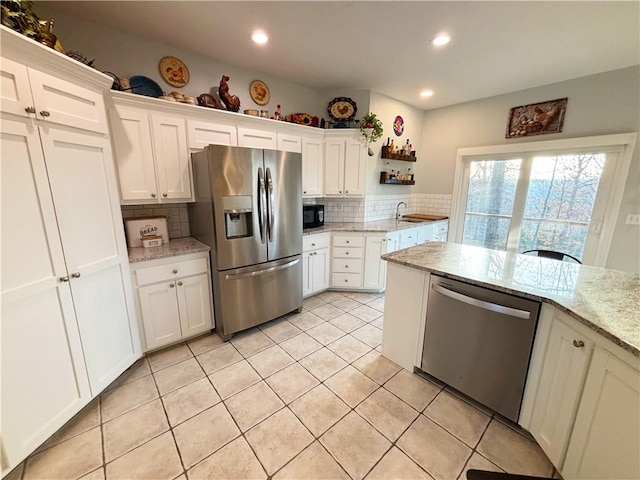 kitchen with light tile patterned floors, light stone countertops, white cabinets, and appliances with stainless steel finishes