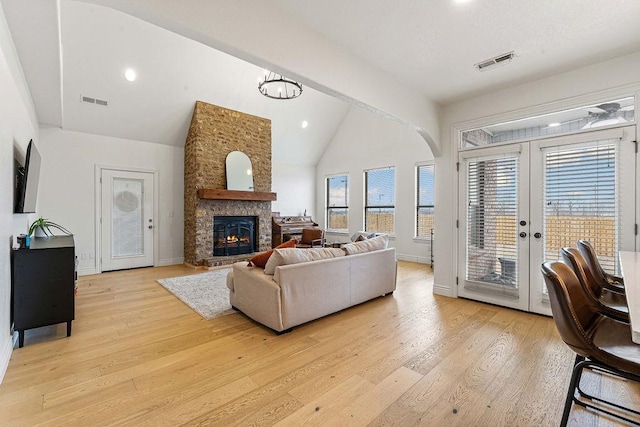 living room featuring french doors, a fireplace, high vaulted ceiling, and light hardwood / wood-style flooring