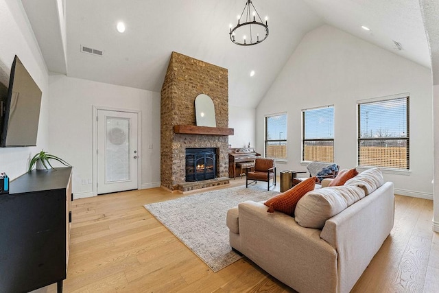 living room featuring a fireplace, high vaulted ceiling, a chandelier, and light wood-type flooring