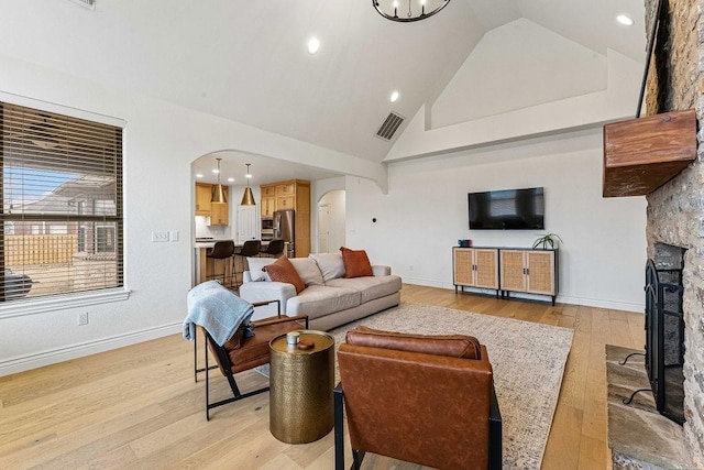 living room with a fireplace, high vaulted ceiling, and light hardwood / wood-style floors