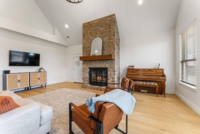 living room featuring high vaulted ceiling, a fireplace, and light hardwood / wood-style flooring