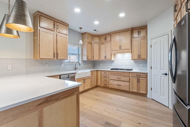 kitchen with sink, light hardwood / wood-style flooring, stainless steel appliances, decorative light fixtures, and light brown cabinets