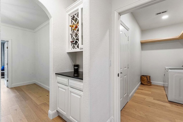 interior space featuring washer and clothes dryer, light hardwood / wood-style flooring, and ornamental molding