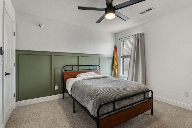 carpeted bedroom featuring ceiling fan and a textured ceiling