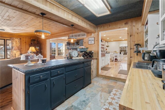 kitchen featuring wood ceiling, wooden walls, blue cabinets, and decorative light fixtures