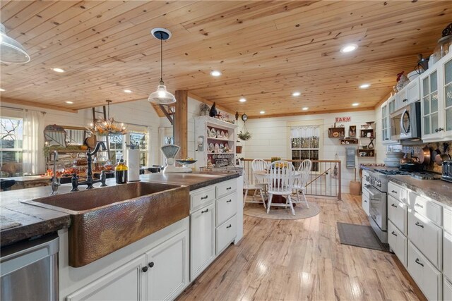 kitchen with pendant lighting, sink, white cabinetry, stainless steel appliances, and light wood-type flooring