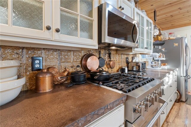 kitchen featuring tasteful backsplash, wooden ceiling, stainless steel appliances, and white cabinets