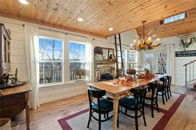 dining area with wood ceiling, lofted ceiling, light hardwood / wood-style floors, and a notable chandelier