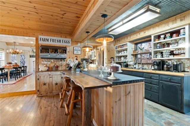 kitchen with sink, wood ceiling, a breakfast bar area, hanging light fixtures, and kitchen peninsula