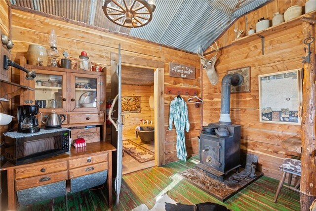 interior space featuring hardwood / wood-style flooring, vaulted ceiling, wood walls, and a wood stove