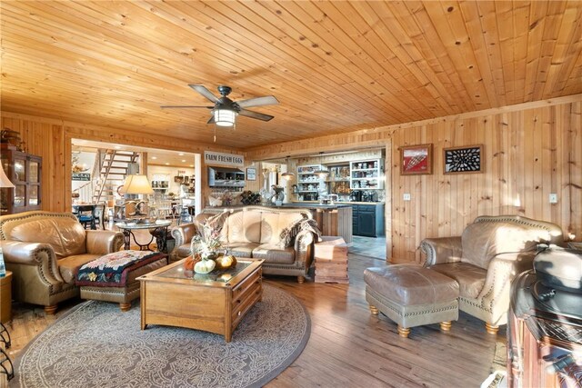 living room with wood-type flooring, wooden walls, ceiling fan, and wood ceiling