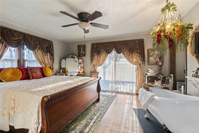 bedroom with multiple windows, ceiling fan, access to exterior, and light wood-type flooring