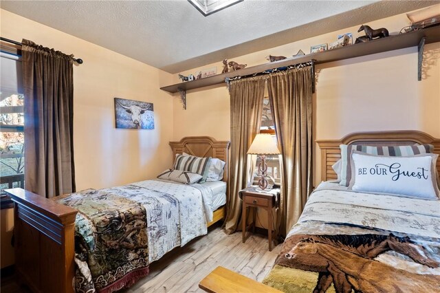 bedroom with a textured ceiling and light hardwood / wood-style flooring