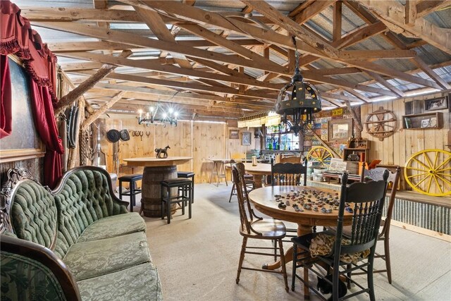 carpeted dining area featuring vaulted ceiling and wooden walls