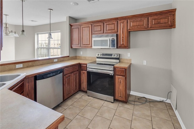 kitchen featuring pendant lighting, light tile patterned floors, sink, and appliances with stainless steel finishes